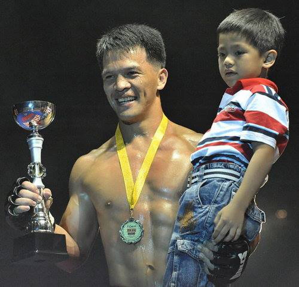 Mark carrying his MMA trophy and a young Jhanlo