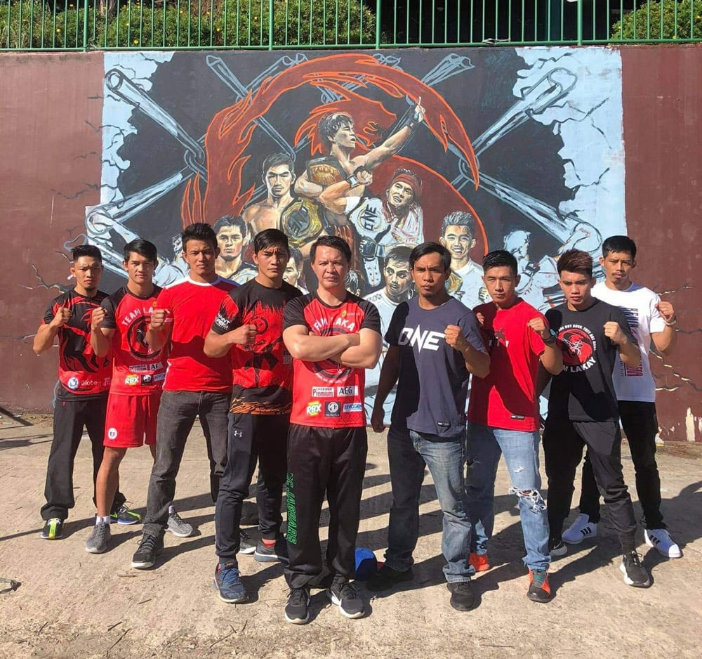 Coach Mark (center) with Team Lakay in front of their mural at the Baguio Athletic Bowl