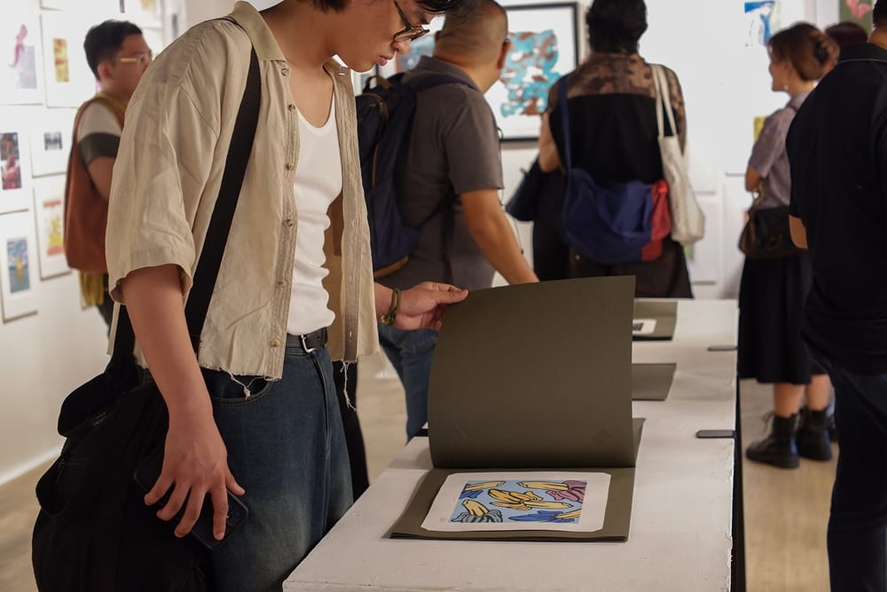 A guest browses through UP Diliman Professor Rey Concepcion’s print portfolios—collections of student works compiled over the years, thoughtfully organized by printmaking technique. While not for sale, the books offer a glimpse into the evolving practices